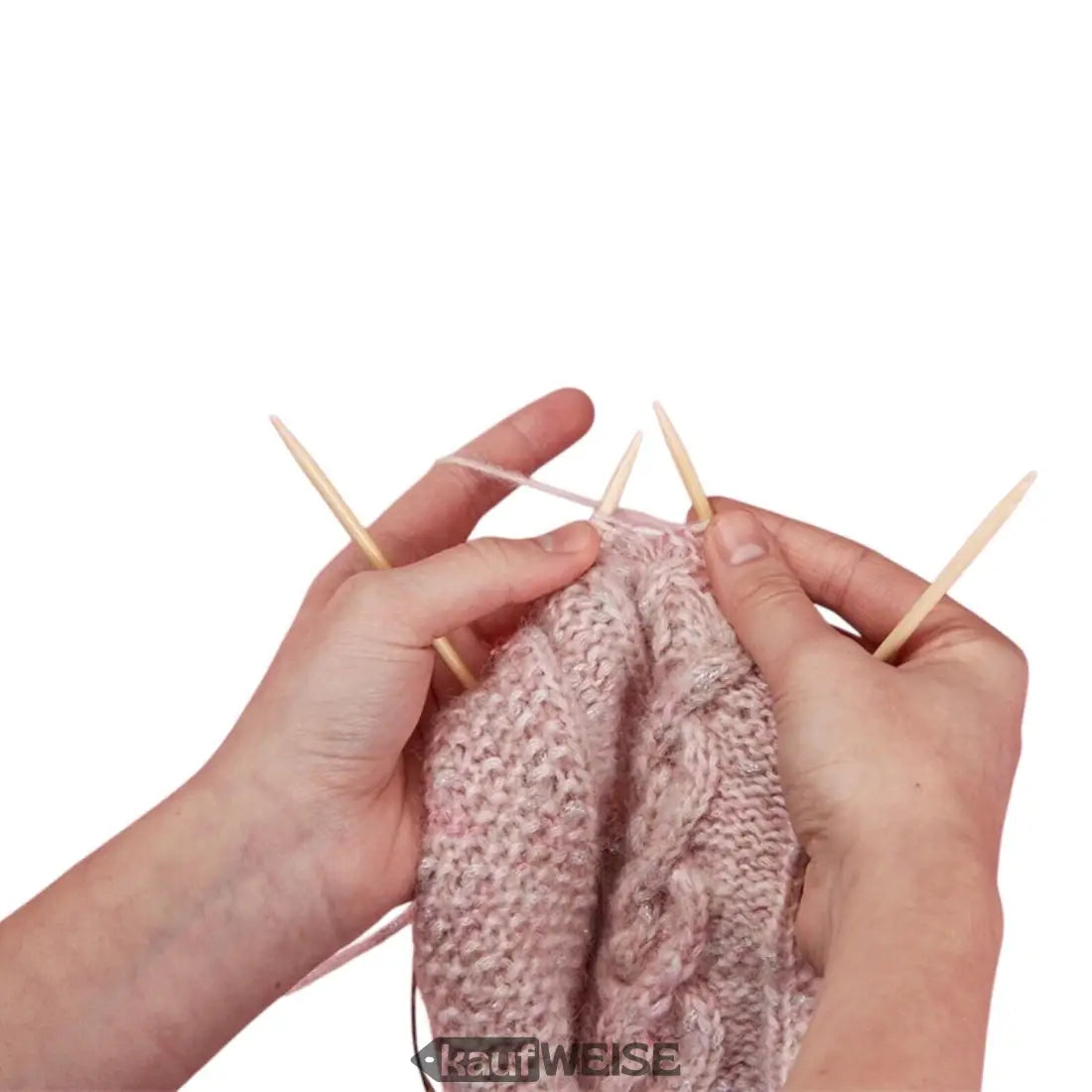 Hände stricken einen rosa Kabelmuster-Pullover mit Holzstricknadeln
